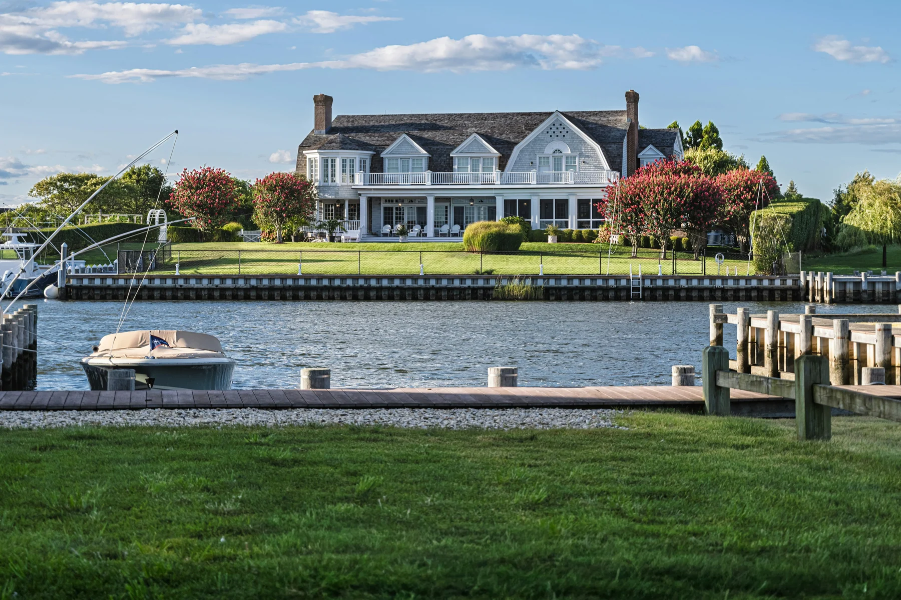 Elegant traditional waterfront residence with a porch, landscaped grounds, dock and boats; illustrative architecture, not a Mississippi location or Watchman project claim